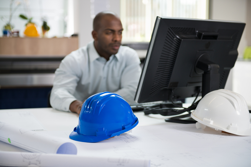Male Architect Studying Plans In Office on Computer.