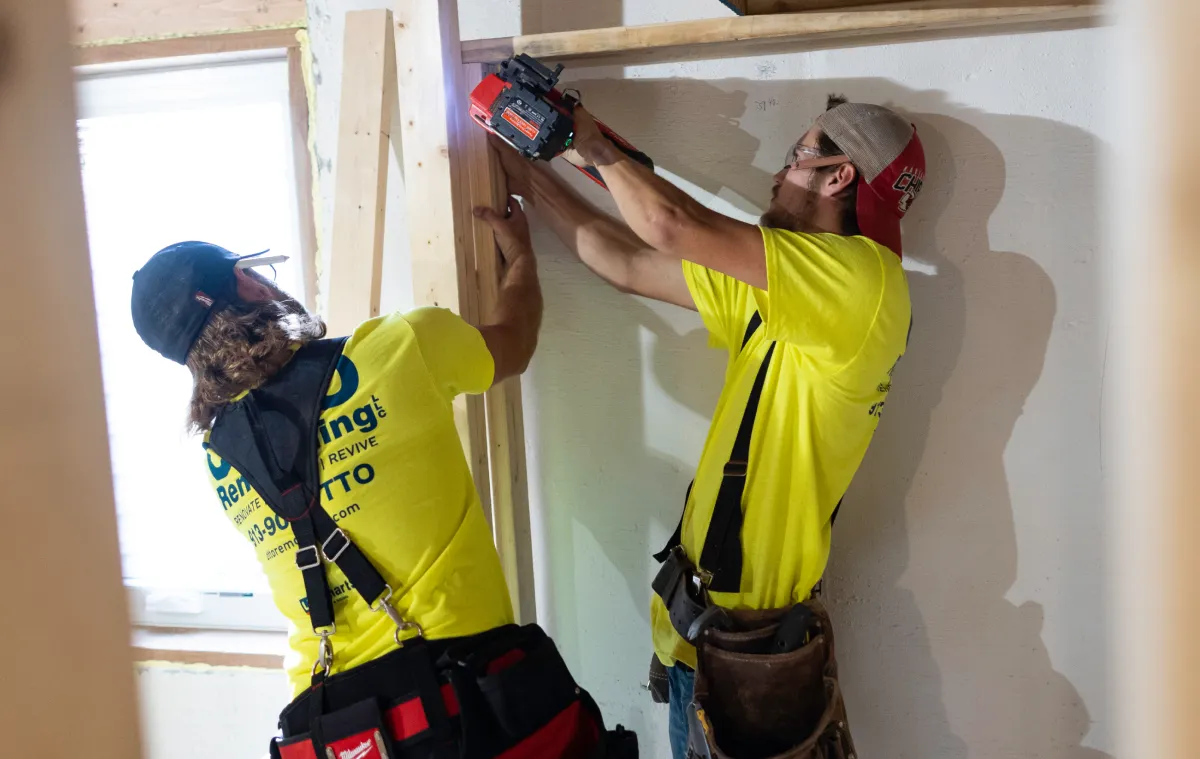 Two men putting up drywall